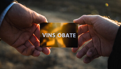 Closeup of Two Hands Holding a Business Card with Vins Obate Text, Golden Light, Concept of Business Networking, Company Brand