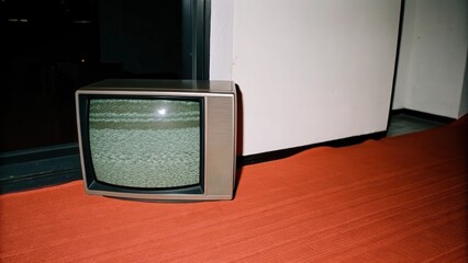 Dark Chirstmas Old television set with static on the screen in an indoor setting.