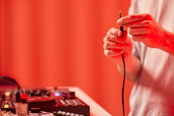 DJ setup closeup, Close view of audio connection process during live performance, Detailed image capturing technician connecting audio cables to mixer with ambient lighting