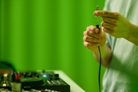 DJ setup closeup, Close view of audio connection process during live performance, Detailed image capturing technician connecting audio cables to mixer with ambient lighting - Powered by Adobe