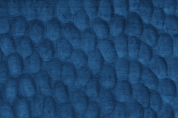 Textured blue wooden surface with carved oval patterns and visible wood grain. Abstract texture background ideal for design, craft, or natural texture themes.