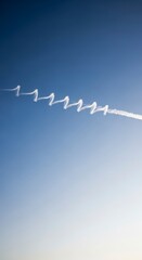 Zigzag Contrail in a Clear Blue Sky with Sun Flare.