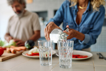Portrait of happy senior mid aged mature couple prepering meal with fresh vegatebles in kitchen at hpme