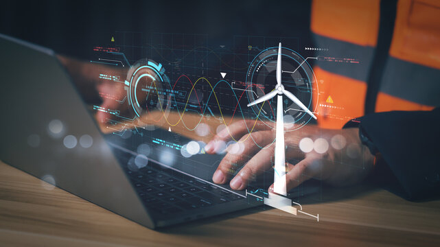 Engineer hands typing on laptop with futuristic wind turbine hologram overlay. Sustainable renewable energy technology and smart grid data analysis concept for modern eco friendly industry.