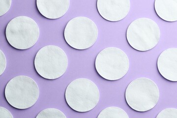 Clean cotton pads on lilac background, flat lay