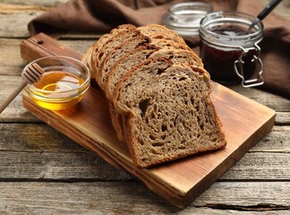 Bread slices with honey and jam on wooden table