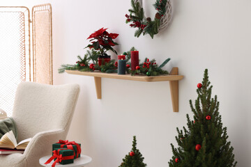 Stylish room with small spruce tree, armchair and Christmas decor. Interior design