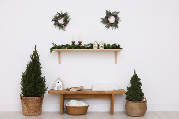 Stylish room with small spruce trees, burning candles and Christmas decor. Interior design
