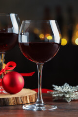 Glasses of red wine and Christmas decor on wooden table indoors
