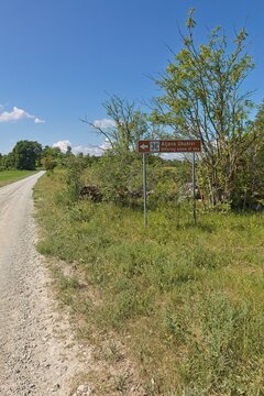 Road sign to Aljava Ukukivi (Offering stone of Uku) along a dirt road in sunny summer weather, Muhu, Estonia.