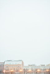 Festive string lights glow against city buildings. Urban evening scene captures cozy winter atmosphere