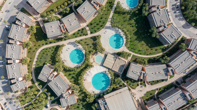 Aerial view of a residential area in Albufeira, Algarve, Portugal. The scene includes several swimming pools surrounded by green spaces and buildings
