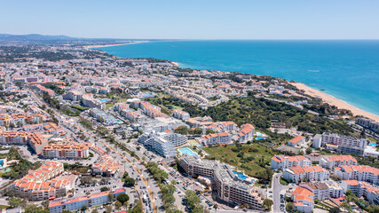 Visitors enjoy the vibrant atmosphere of Albufeira marina with buildings, beaches, and clear blue waters in Algarve, Portugal on a sunny day