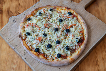 Freshly baked pizza topped with olives and cheese, served on a wooden board, showcasing delicious culinary artistry and vibrant colors