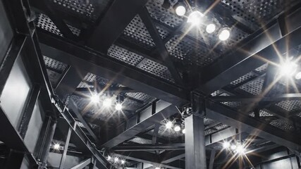 Industrial ceiling with bright lights and metal beams. - Powered by Adobe