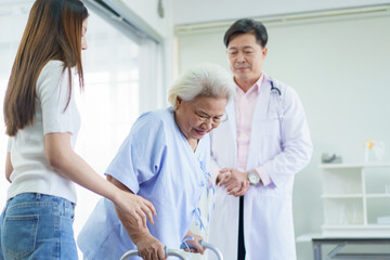 Obraz premium An elderly patient practices walking with a walker under medical supervision.