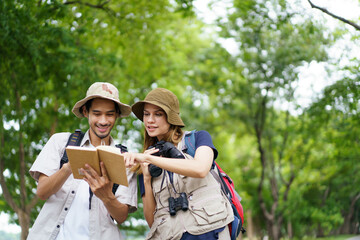 Two explorers use a notebook and binoculars while navigating through the forest.
