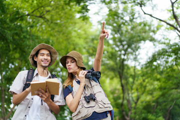 Two explorers use a notebook and binoculars while navigating through the forest.