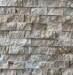 Natural beige stone wall texture with raw, uneven surface and detailed mineral patterns. Perfect for backgrounds, architectural design, construction themes and material references.