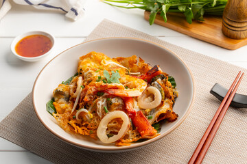 Oyster omelette seafood,Pan fried crispy green mussels, squid, shrimps, Crab sticks with bean sprout,Thai crispy pancake in white plate.