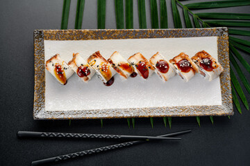 Glazed Eel and Salmon Roll with Sweet Sauce. Eight slices of maki rolls, featuring unagi eel and salmon, are drizzled with a rich, dark sauce. © Анна Терелюк