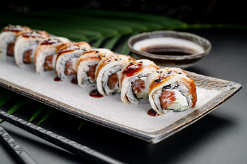 Glazed Eel and Salmon Roll with Sweet Sauce. Sliced maki rolls, featuring salmon and cream cheese, are topped with caramelized eel and sweet glaze.