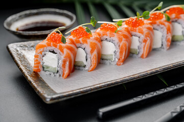 Salmon Maki Rolls with Cream Cheese and Roe Topping. A row of vibrant salmon rolls filled with cream cheese and cucumber is crowned with bright red caviar. © Анна Терелюк
