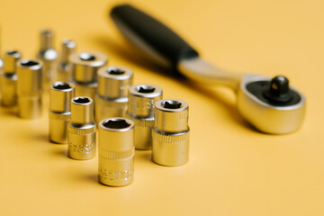Various socket tools and a ratchet placed on a yellow background for a workshop setup