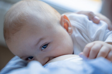Baby infant looking at camera while breastfeeding
