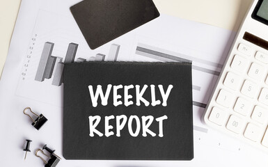 Text weekly report written on black paper with charts, calculator, and office supplies