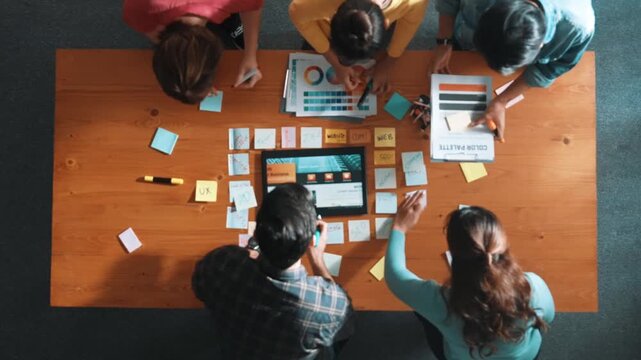 Time lapse of business people working together to design web design. Aerial view of designer brainstorming and discussing about website interface and looking at tablet with digital design. Symposium.