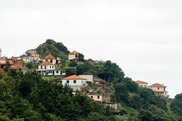 Fototapeta premium Scenic hillside village with colorful houses nestled among lush greenery, showcasing a tranquil landscape and charming architecture in a serene natural environment