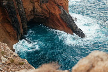 Rocky coastal cliff with turquoise waves crashing against the shore, showcasing the beauty of nature and the power of the ocean in a serene landscape