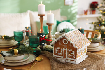 Festive table setting with beautiful gingerbread house and Christmas decor indoors, closeup