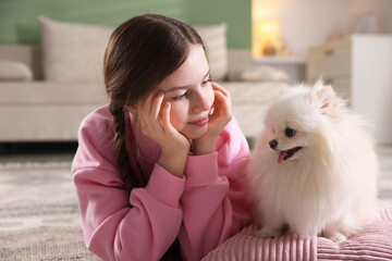 Teenage girl with Pomeranian dog on floor at home