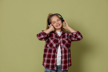 Cute little girl in headphones on olive background