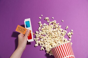 Woman with movie ticket, 3D glasses and tasty popcorn on violet background, top view