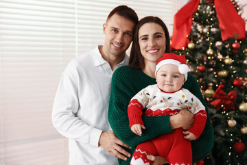 Happy parents with their cute baby in room decorated for Christmas