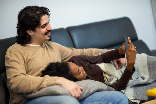 Couple relaxing on sofa watching tablet
