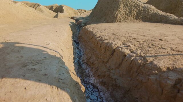 A close-up showing the feet of a traveler clad in ancient rope sandals, standing beside a prominent rock on parched, cracked earth. Christian and spiritual concept