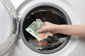 Woman putting euro banknotes into washing machine, closeup