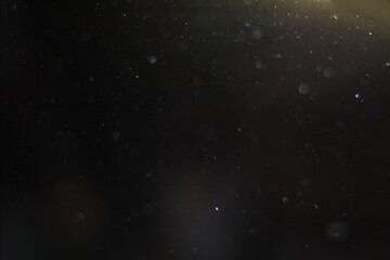 Naklejka premium Gentle curtain of soft dust particles illuminated by subtle top light, floating in dark moody space to create delicate cinematic overlay texture that adds quiet atmosphere, depth and realism to film 