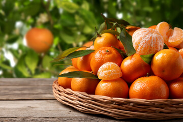 Fresh juicy tangerines on wooden table near tree outdoors
