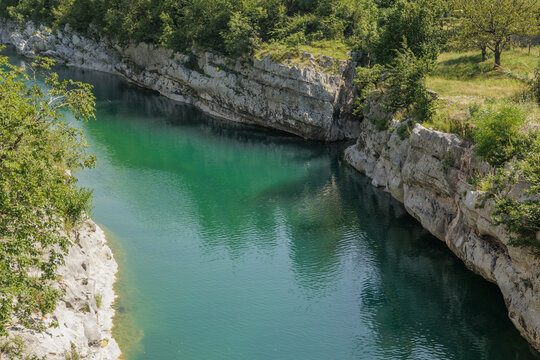 dettagli delle alte sponde rocciose del fiume Isonzo tranquillo, con le sue acque color verde smeraldo, durante il giorno, in estate, in Slovenia