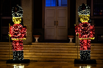 Festive decorative Christmas soldiers adorned with glowing string lights on a public square in Durrës, Albania.