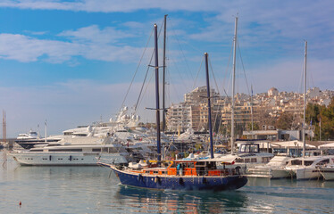 Fototapeta premium Large yachts moored in the harbor of Piraeus, Greece with city buildings in background