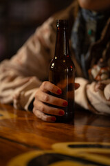 Close up of Woman's Hands Holding Beer Bottle at Bar in Rustic Rural Western Saloon Bar