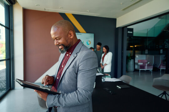 Side view of black mature businessman using tablet in meeting room at workplace