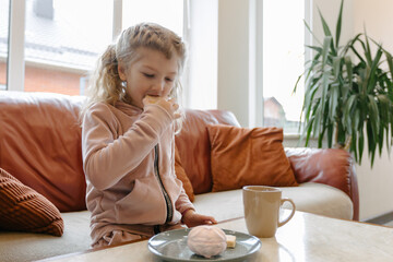 Young girl eating breakfast on couch in cozy living room setting