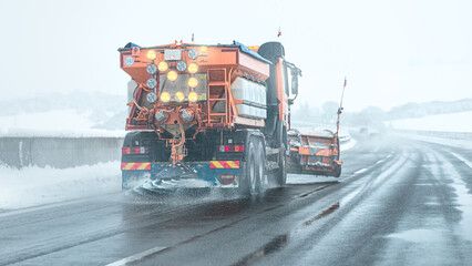 Snow plow sprinkles highway with road salt in freezing weather. © Sabrewolf